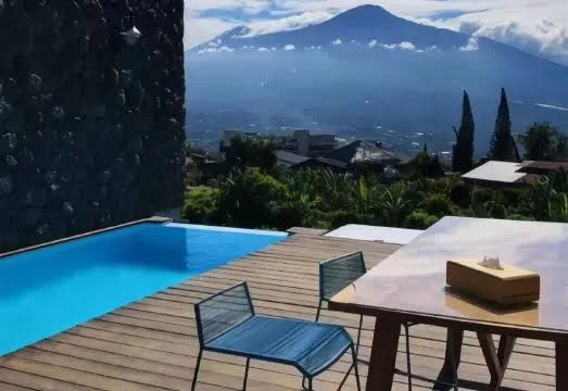 Kolam renang dan taman di The Cendana Villa & Resort, menunjukkan suasana privat penginapan unik di Malang.