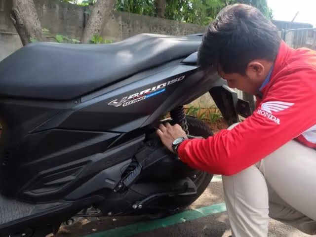 Seorang pria sedang melakukan pemeriksaan ban, bagian dari hal wajib cek kondisi motor sewaan